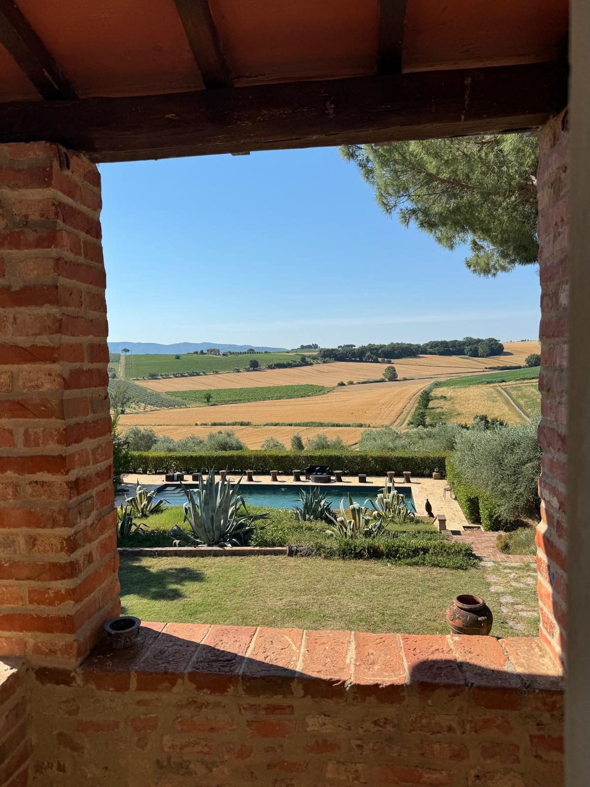 La piscina e i campi, visti da un'apertura nel muro di mattoni